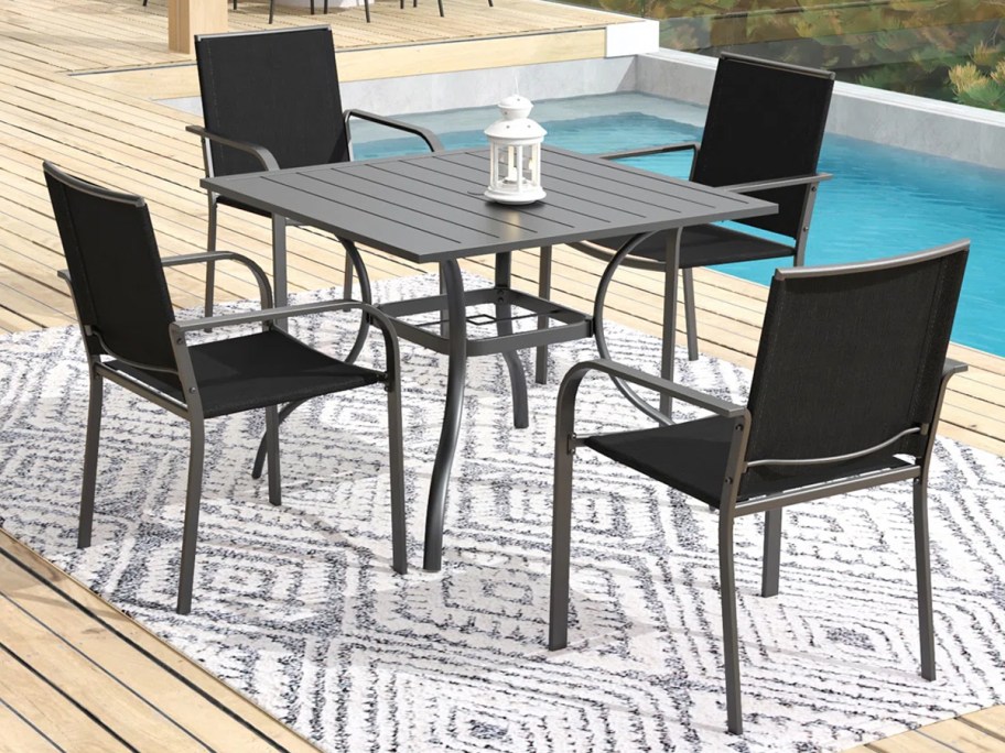 black dining table with chairs next to the pool 