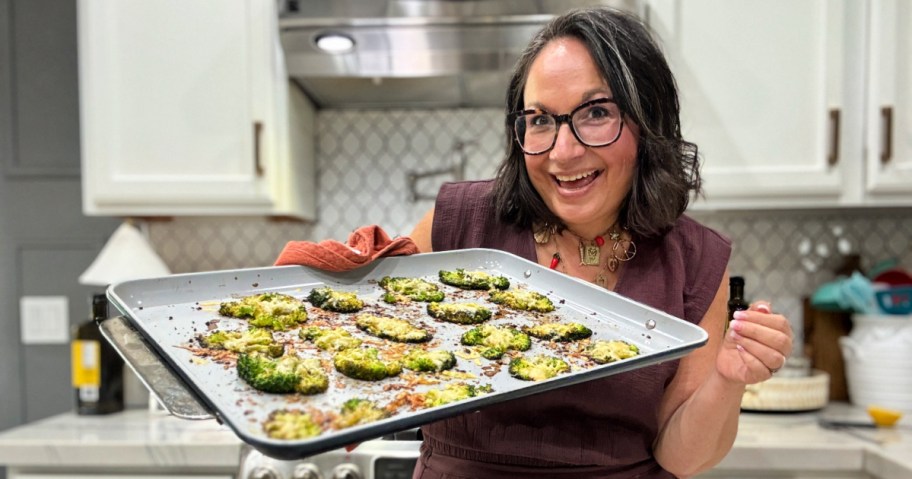 woman holding a sheet pan of smashed broccoli