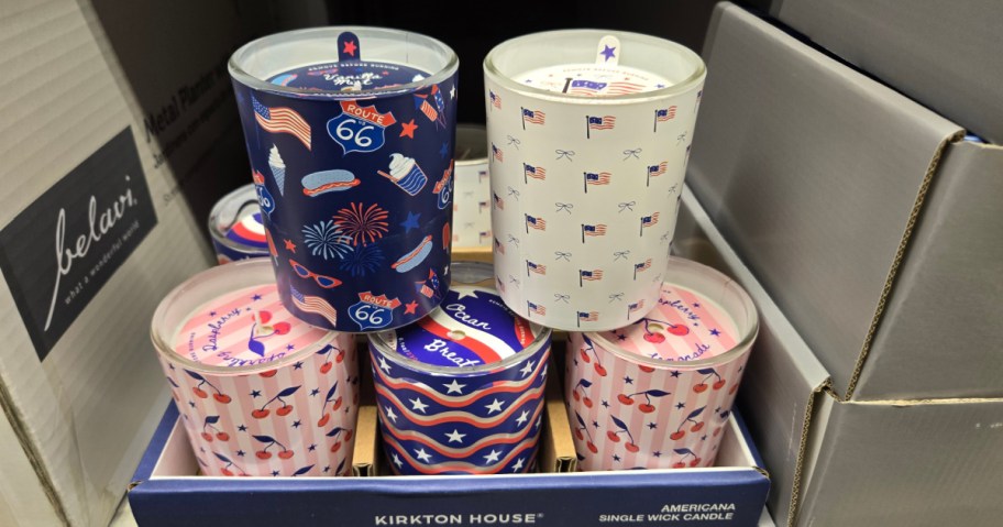 Display of candles with Americana designs, featuring Route 66, fireworks, and flags in blue, white, and red hues.