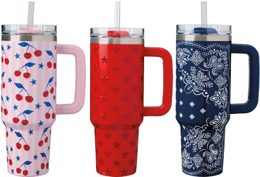 Three tall tumblers with handles, featuring a pink cherry pattern, red stars, and a navy floral bandana design. Each has a lid and straw.
