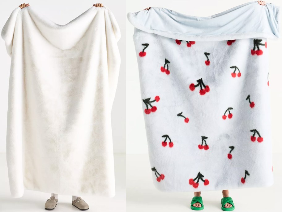 two people holding up fluffy throw blankets