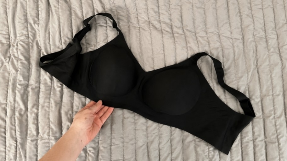 a womans hand lifting edge of black jelly bra