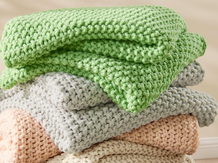 stack of knit throw blankets in various colors