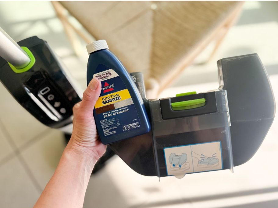 Hand holding part of a Bissell SpinWave + Vac Cordless Mop & Vacuum and cleaner