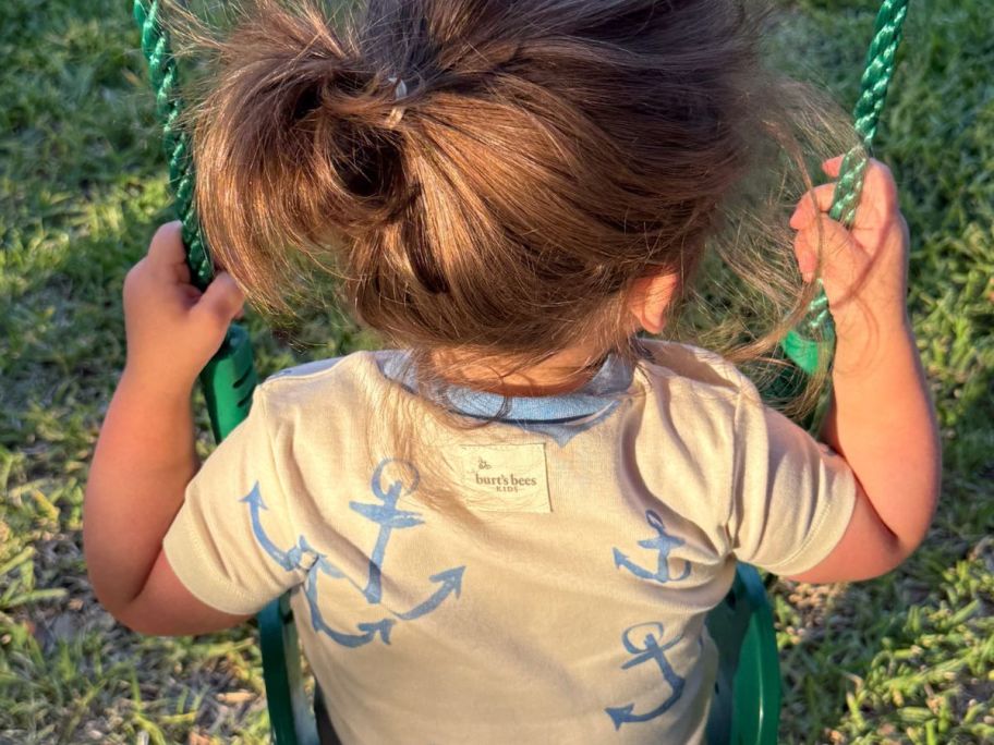 little girl on a swing wearing Burt's bees baby pajamas