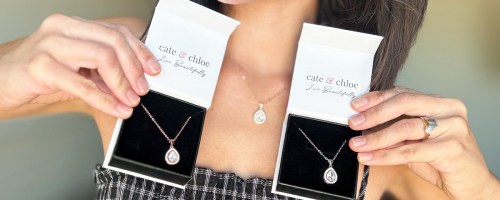 woman holding up two boxed necklaces