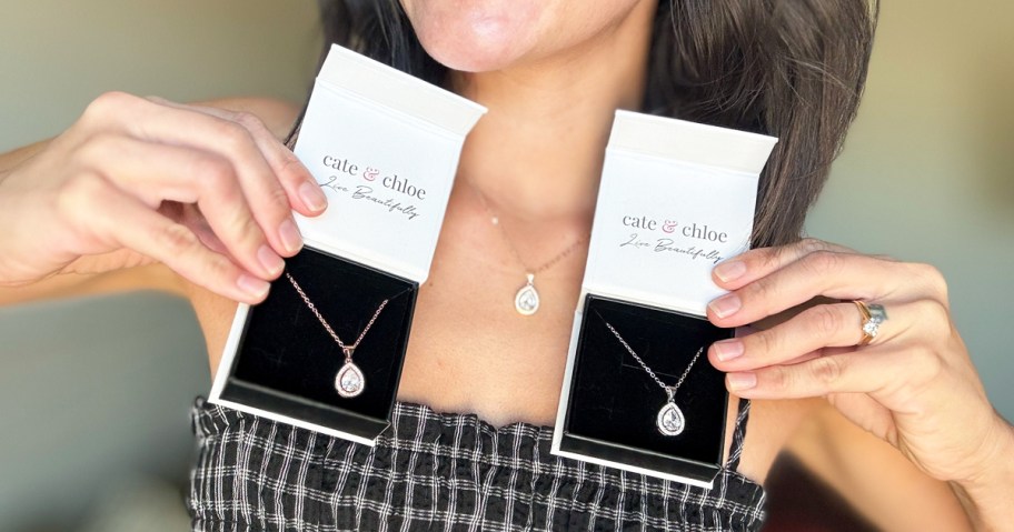 woman holding up two boxed necklaces