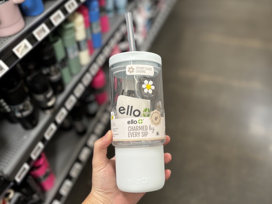 person holding ello charm tumbler with daisies and blue silicone boot