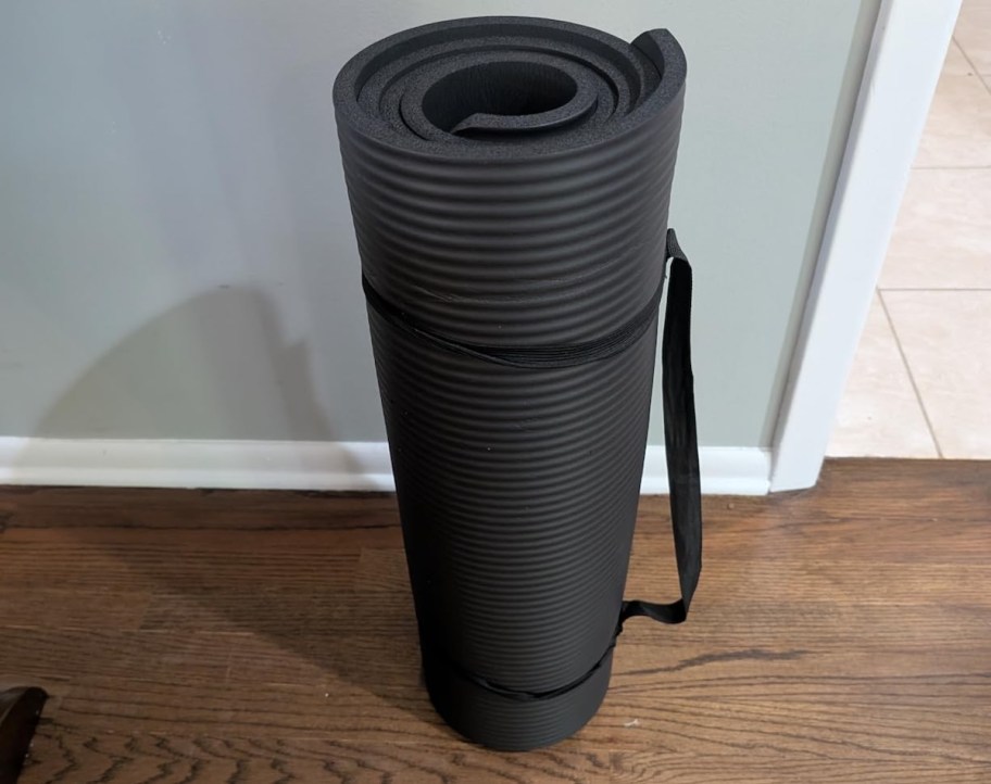 black rolled up exercise mat on floor