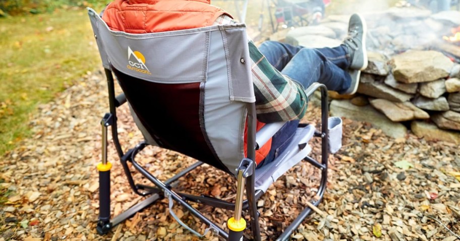 person sitting by campfire in a grey rocker chair