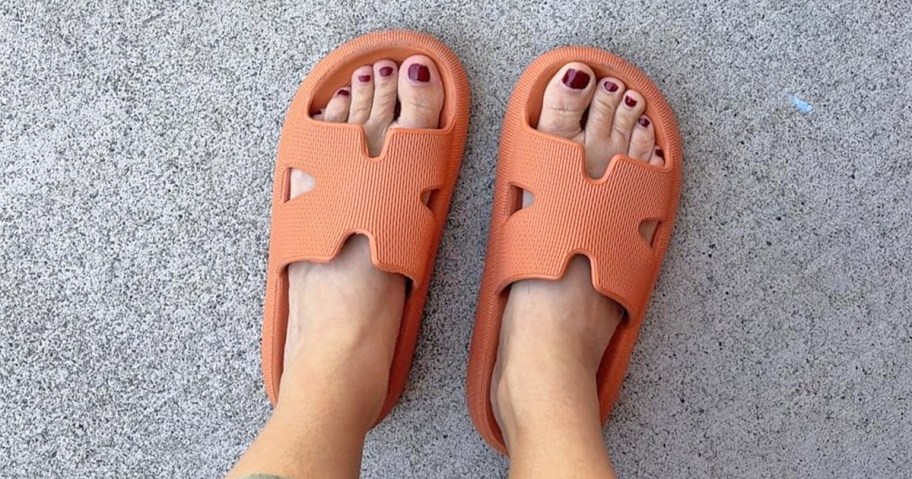 woman wearing a pair of orange cloud slides
