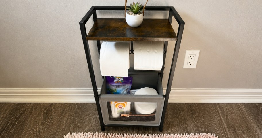 a small bathroom storage unit with a toilet paper holder 