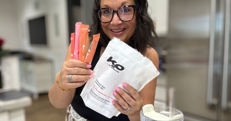 Woman holding a packet of K20 Hydration Packets in one hand and four indivdiual drink sticks in the other