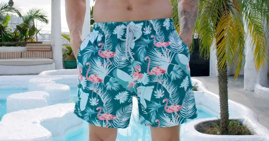 man wearing blue flamingo print swim trunks