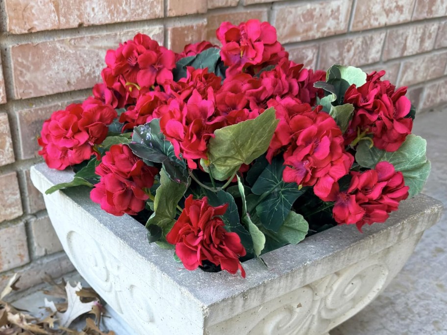 red faux geranium flowers in a concrete planter