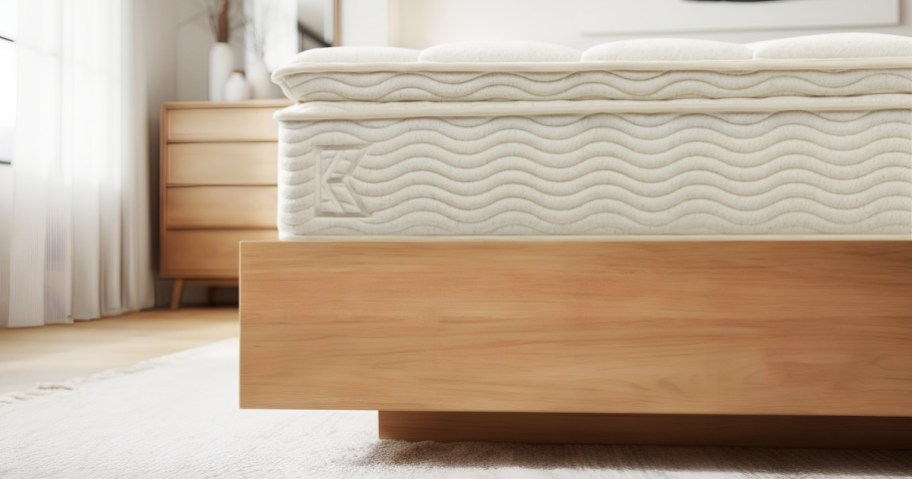 A cozy bedroom features a light wood bed frame with a wavy-patterned mattress.