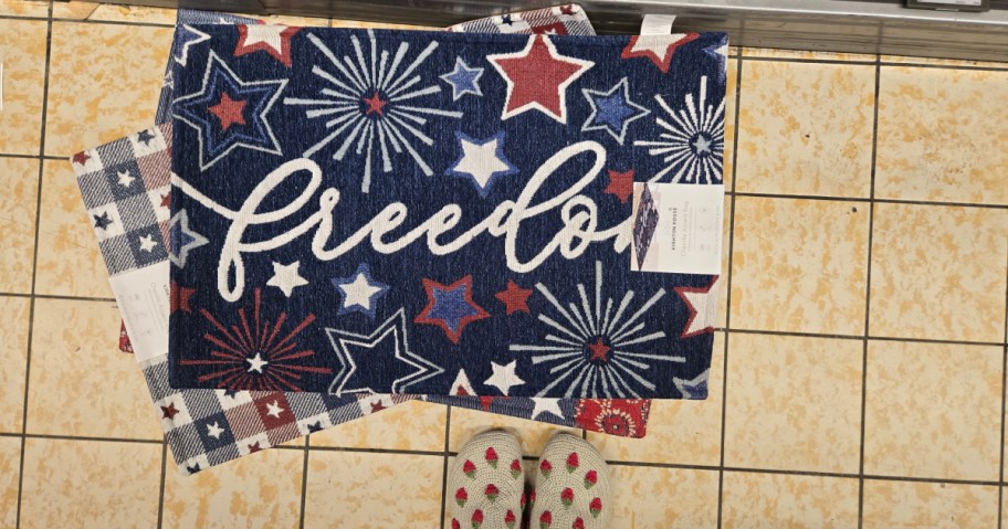 Doormat with "freedom" in cursive, adorned with red, white, and blue stars and bursts.