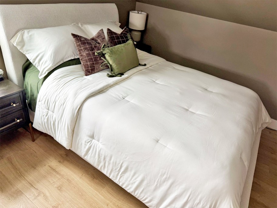 A bed with a white Litanika comforter set on it