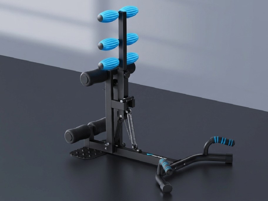 Compact exercise equipment with blue-padded grips and black metal frame on a dark surface.
