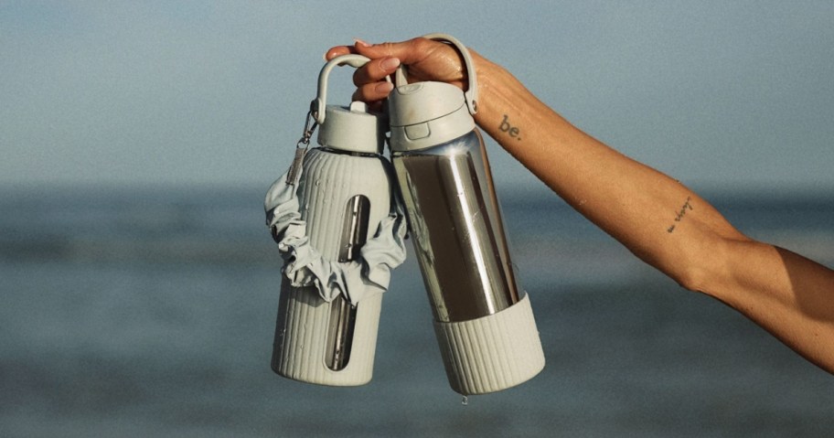 woman holding TAL Mary Lawless Lee water bottles with strap and silicone boots