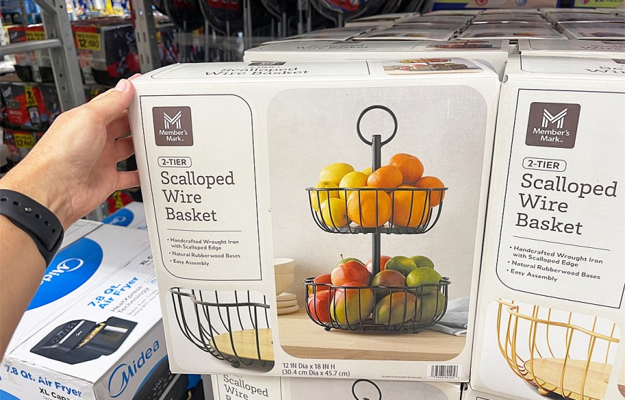 hand touching the box to a Member's Mark Scalloped Wire Basket on store display