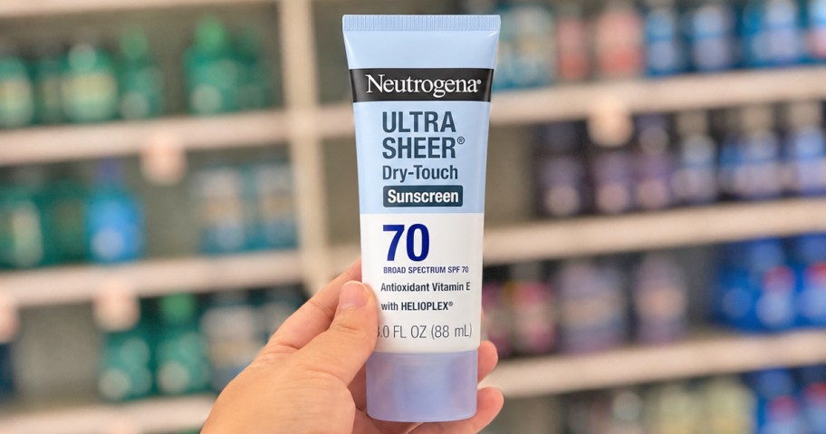 hand holding a bottle of Neutrogena Ultra Sheer Sunscreen in store aisle