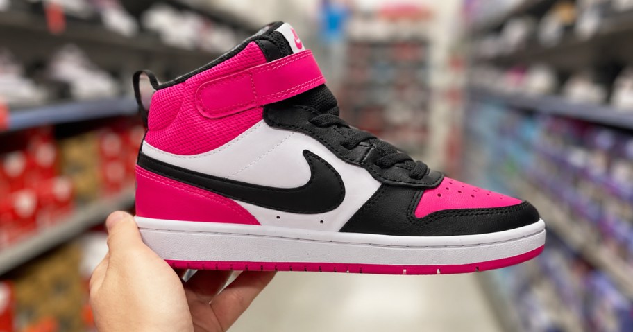 hand holding up a black, white, and pink nike kids sneaker