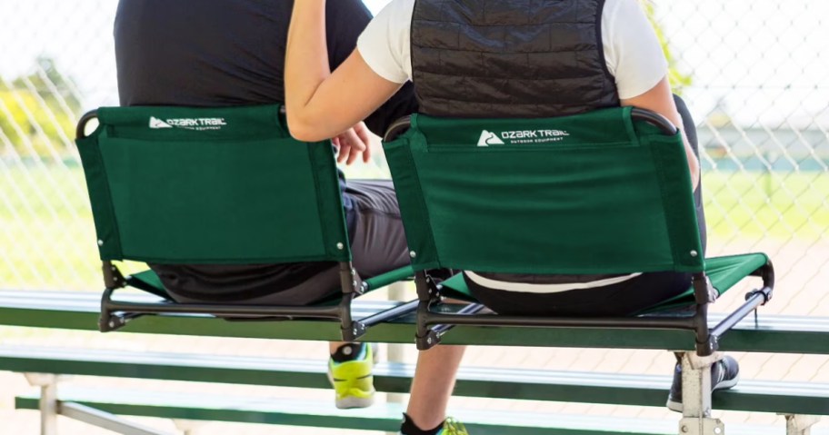 two people sitting in green stadium seats on bleachers