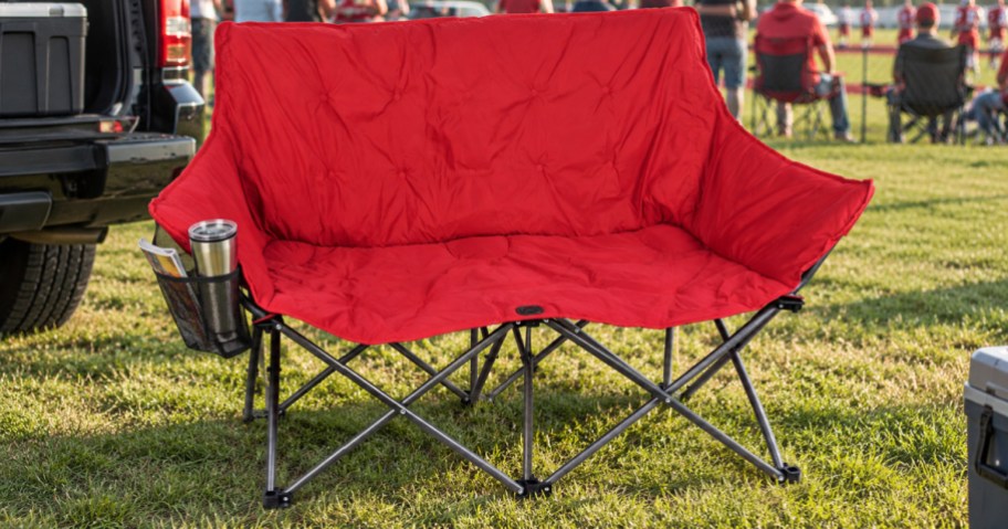 Red padded loveseat on grass