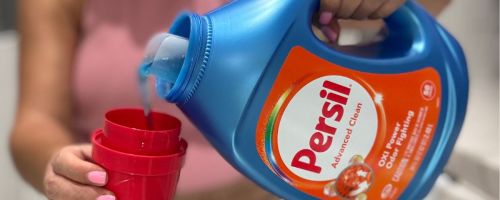 woman pouring Persil laundry detergent from the bottle into the cap