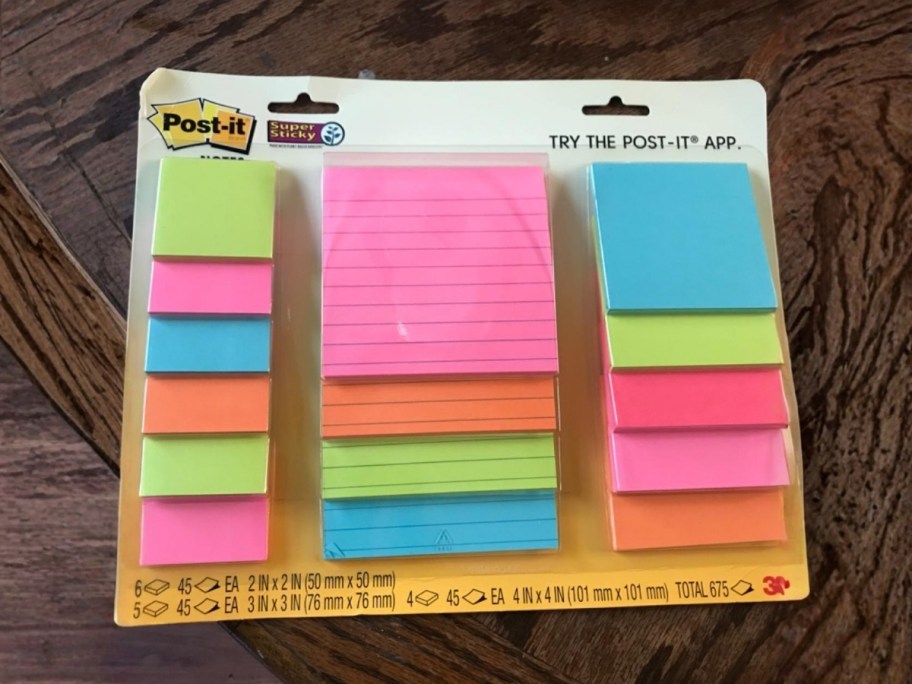 package of post-it notes in 3 different sizes sitting on wooden table