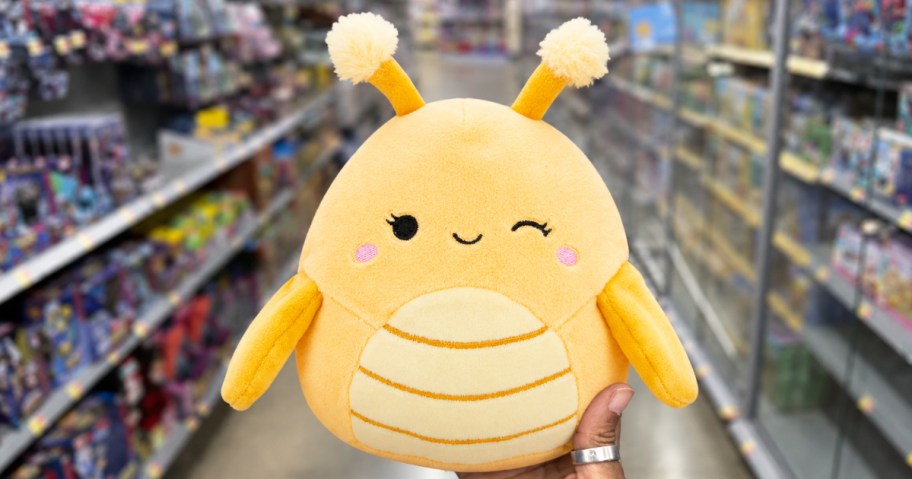 hand holding up a yellow grasshopper plush in store