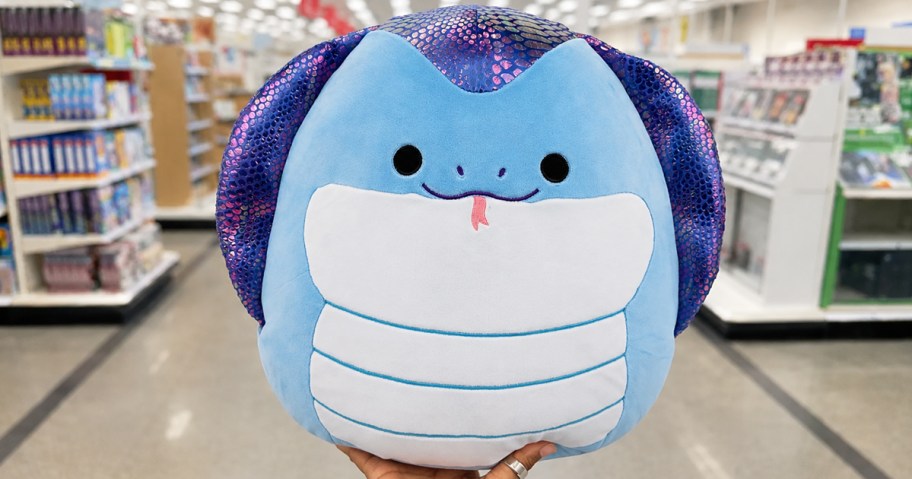 hand holding up a blue snake squishmallows plush in store