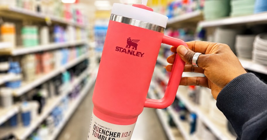hand holding up a bright red stanley tumbler in store