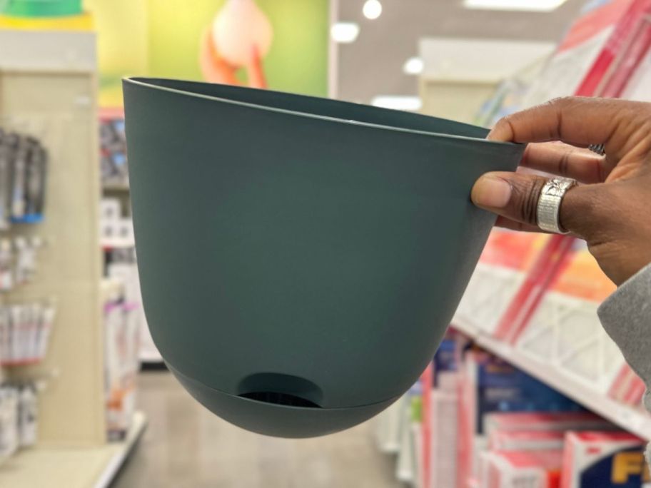 Hand holding a selft watering planter from target