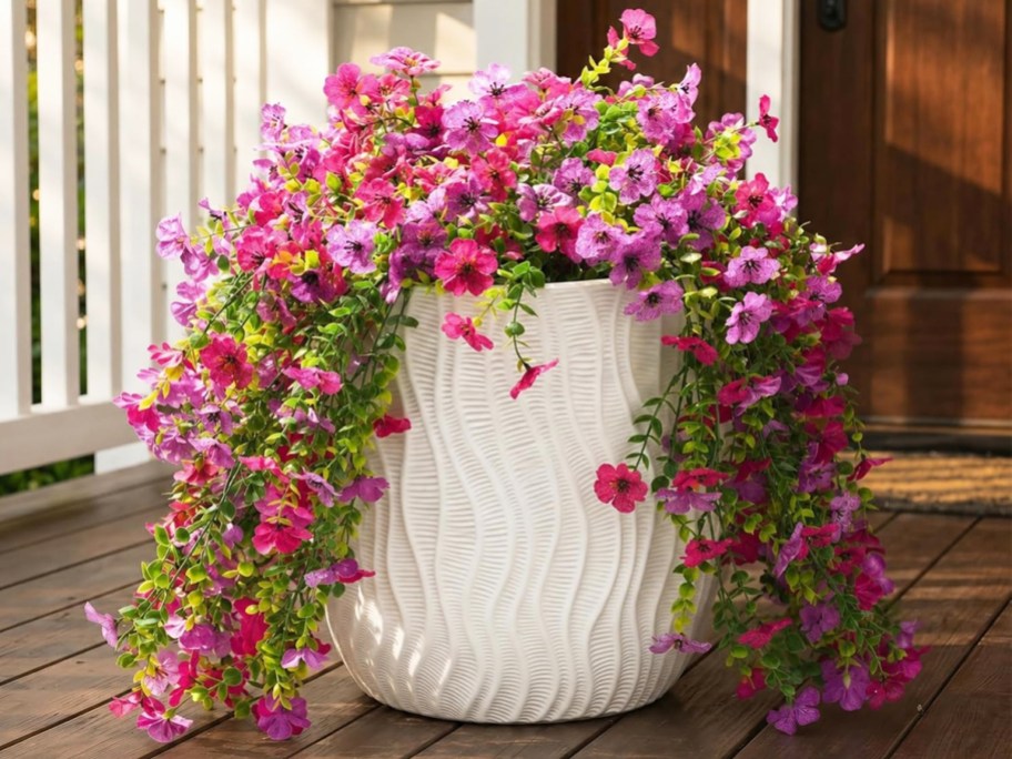 pink and purple artificial flowers in a white planter