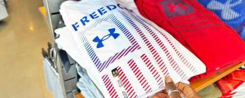 hand grabbing a under armour freedom flag shirt from store display table