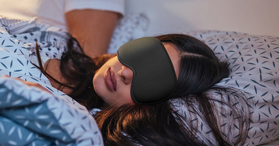 woman in bed with a black sleep mask on her face