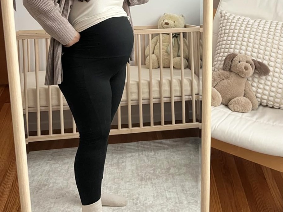 woman taking photo in mirror wearing black maternity leggings