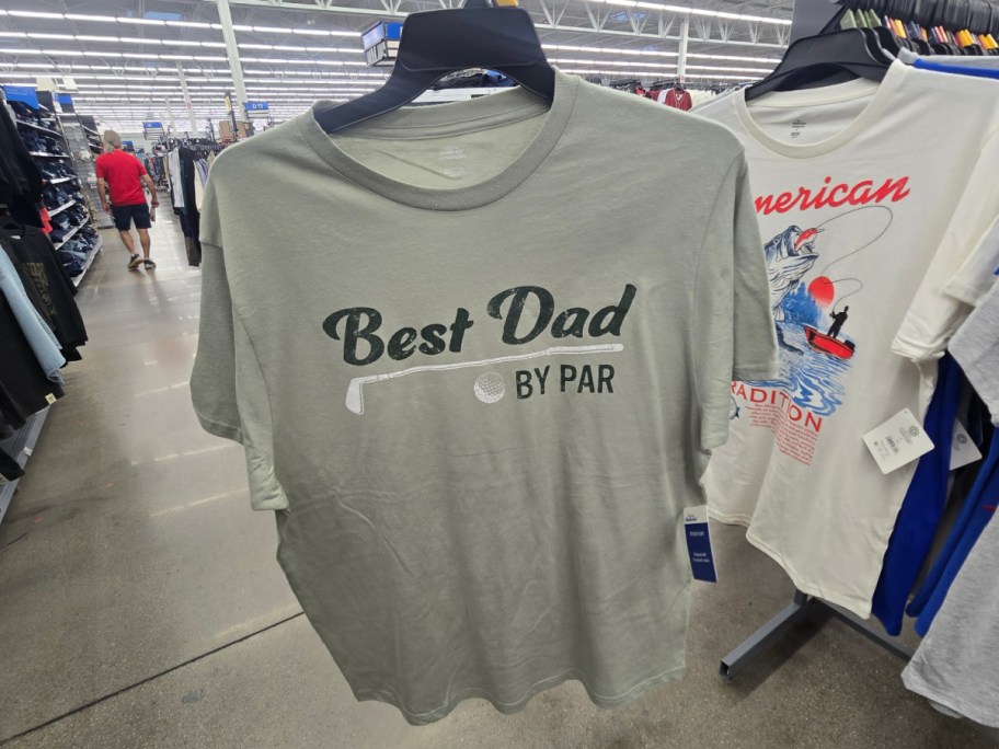 A gray t-shirt hanging on a display rack with the text "Best Dad BY PAR" printed on it.