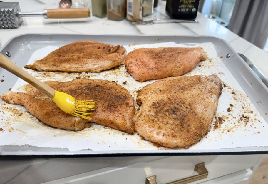 adding seasoning to chicken breasts 