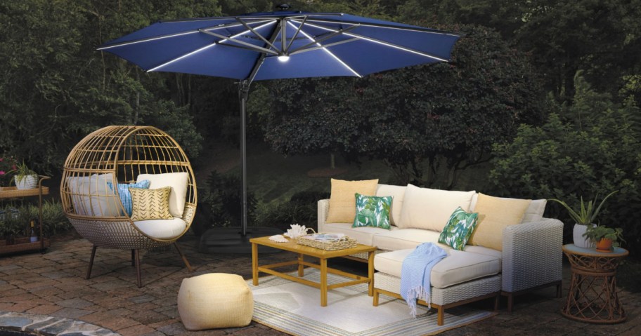 Large blue patio umbrella with lights outside on stone patio