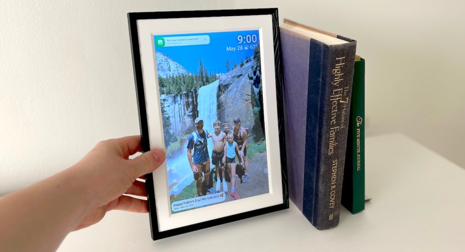 hand holding side of digital picture frame with family waterfall photo