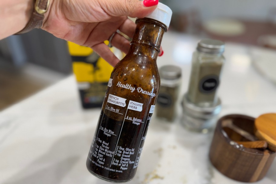 hand holding salad dressing bottle with recipes on it