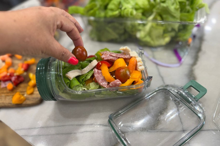 hand grabbing tomato from side jar salad bottle