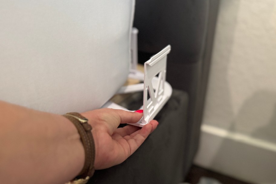 hand grabbing clip on corner of bed