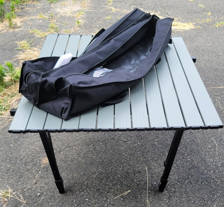 a gray outdoor camping table and carry bag, set up outside