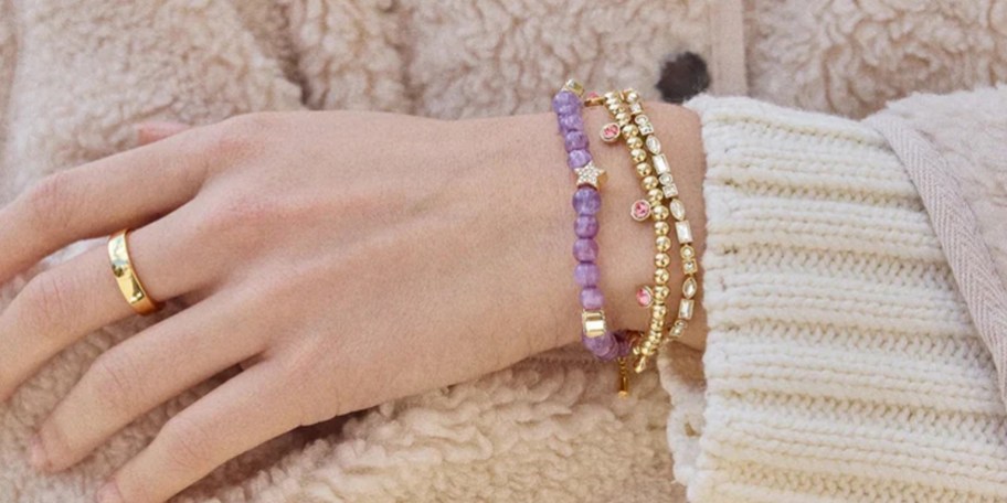 gold and purple bracelets on arm