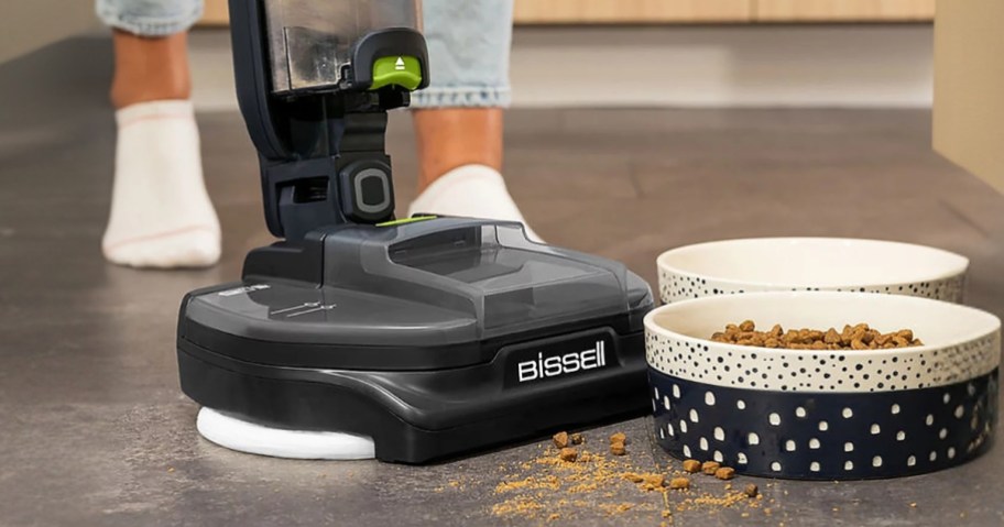 person using a Bissell mop and vacuum to clean up spilled dog food