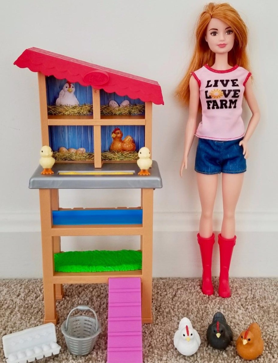 barbie doll standing next to chicken coop